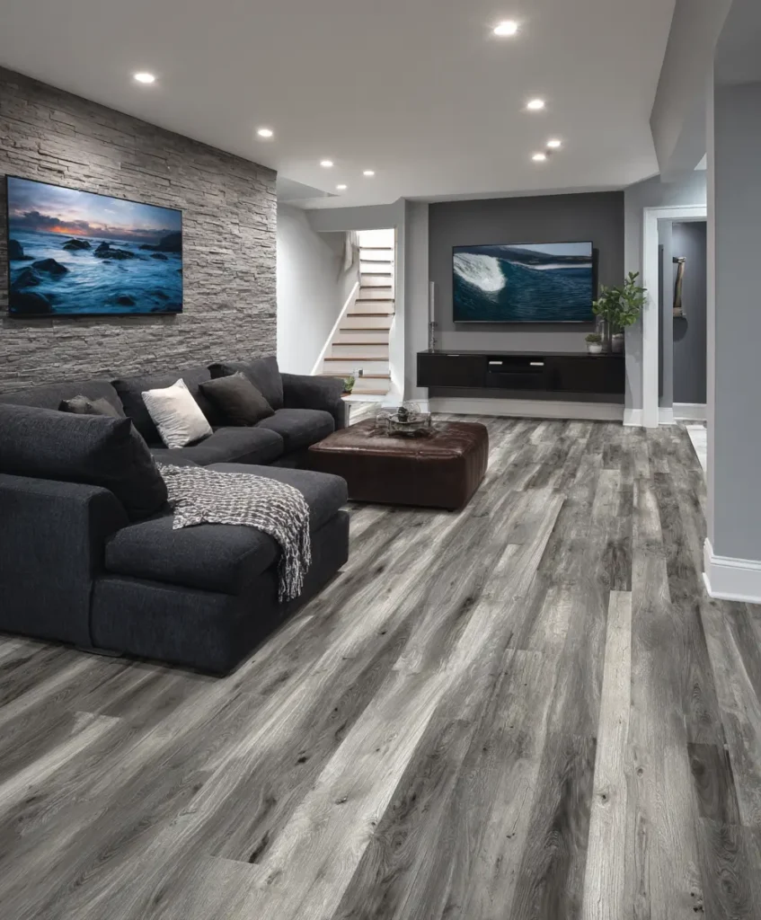 basement entertainment room with wide gray-toned luxury vinyl plank flooring